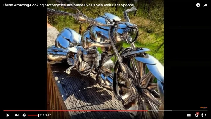 Scultura con soli cucchiai che riproduce in scala una moto