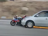Investe un motociclista e fugge con la moto incastrata nell'auto